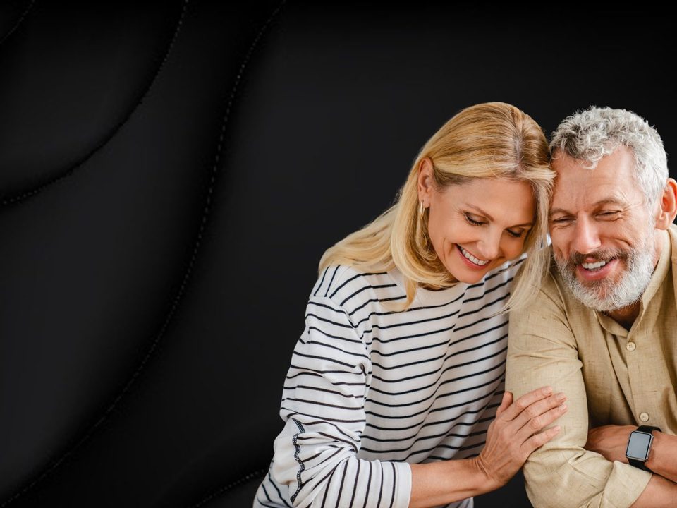 Pareja mayor sonriendo, apoyada el uno en el otro