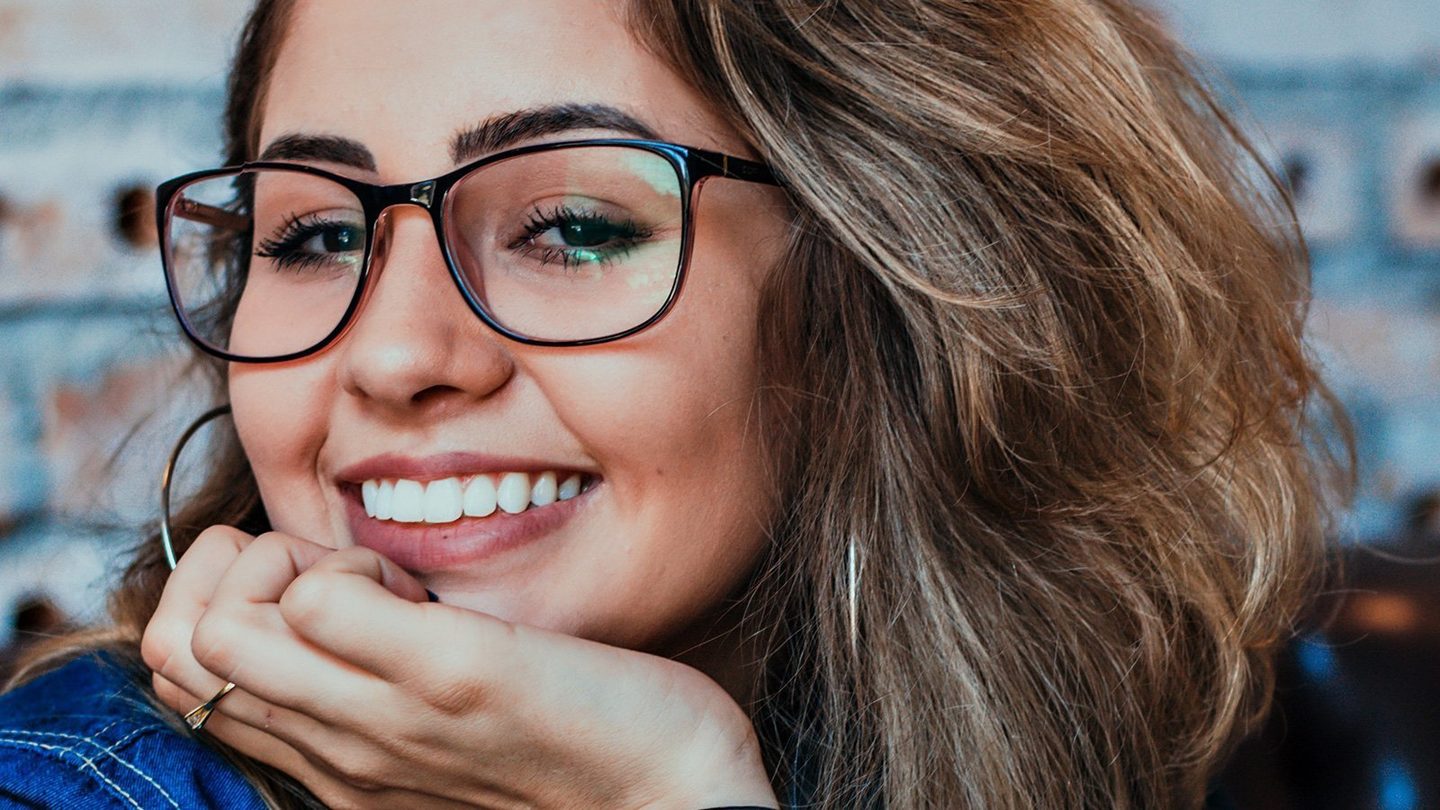 Mujer sonriendo con gafas, dientes blancos